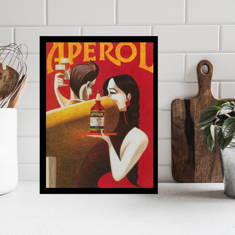 Framed Aperol poster on a kitchen wall with utensils and a plant.
